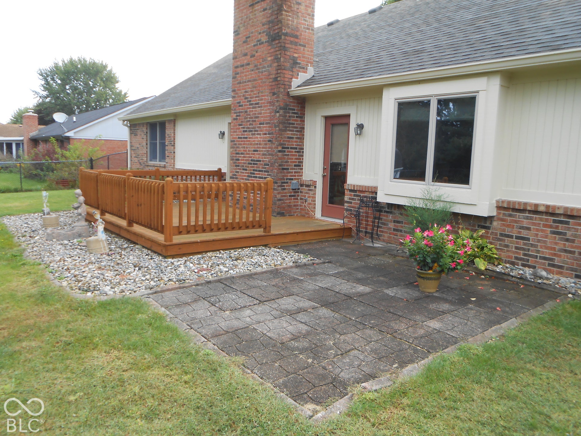 Rear exterior featuring a wood-finish deck, brick chimney.