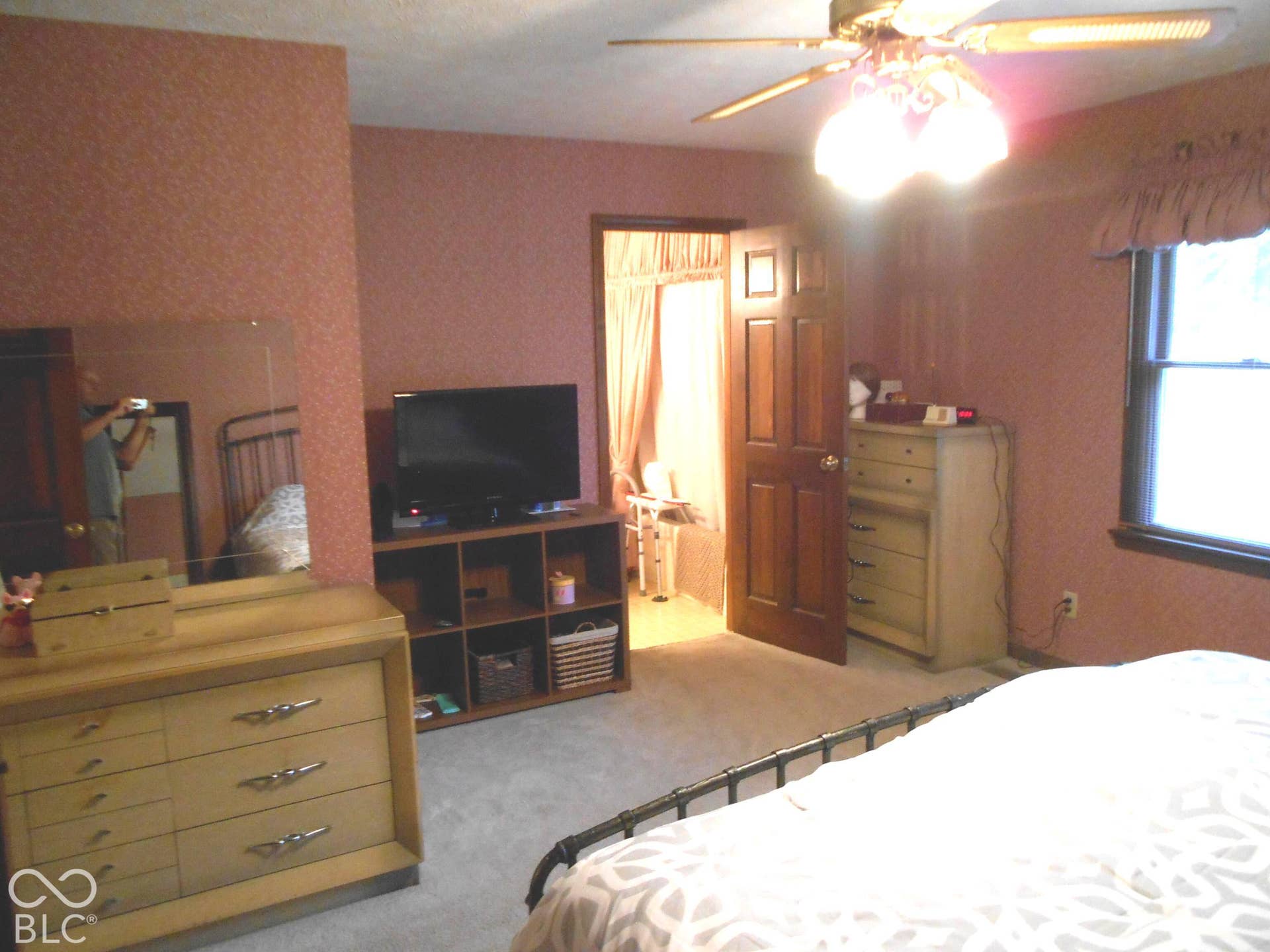Wall-mounted decorative lighting with a ceiling fan, window with dark trim, and a paneled door
