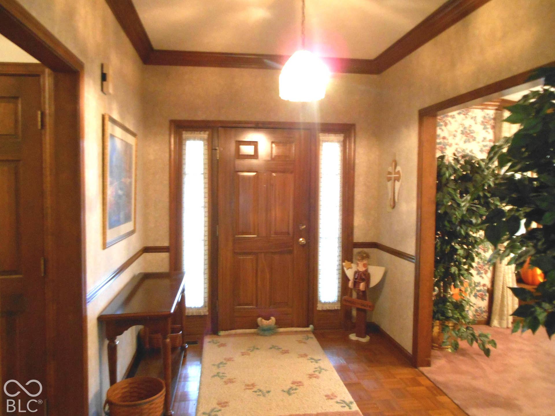Wood-finish flooring, wood-paneled door with sidelights, and crown molding