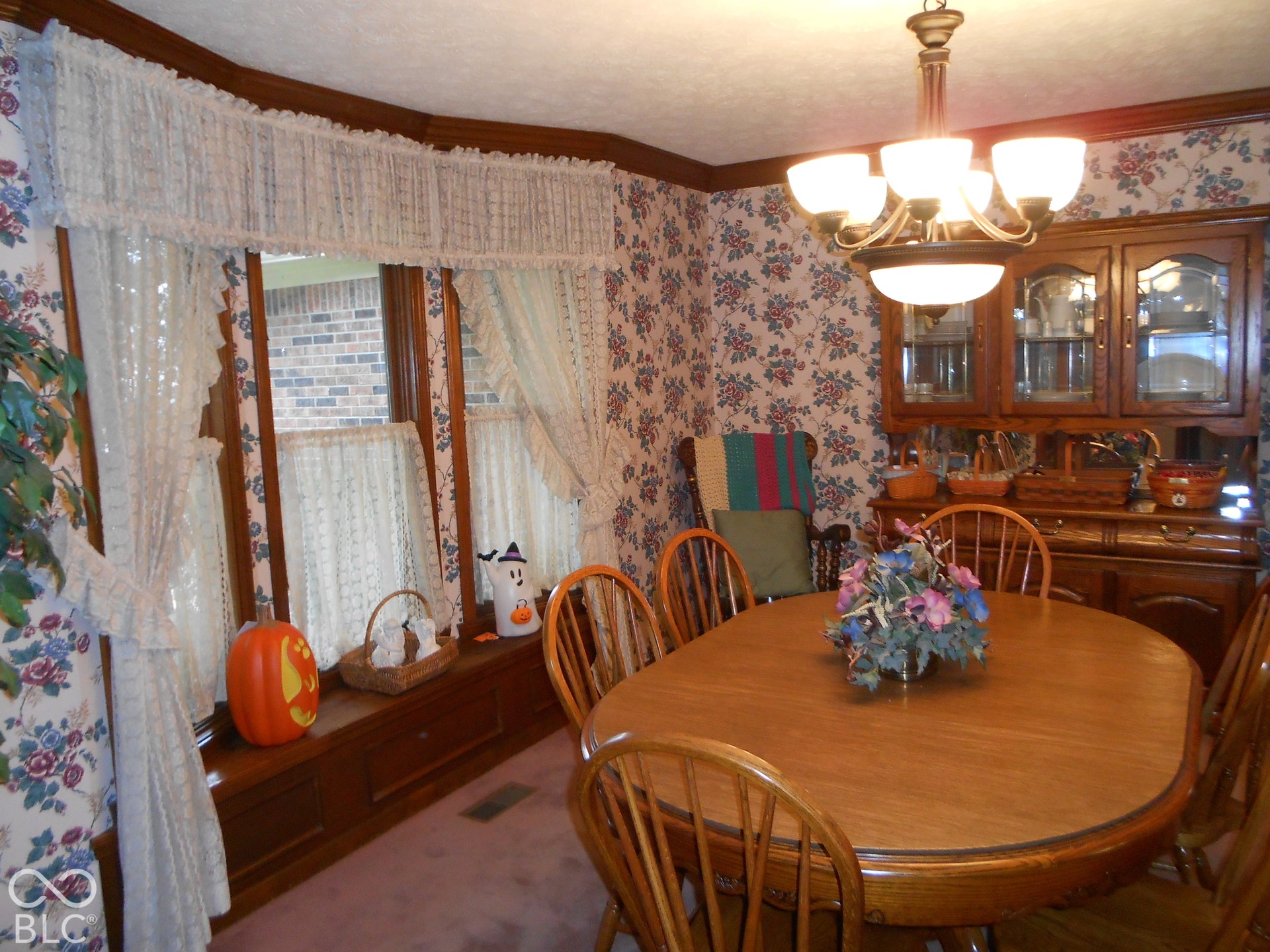 Bay window, wood-finish trim, decorative wallpaper, and an overhead chandelier