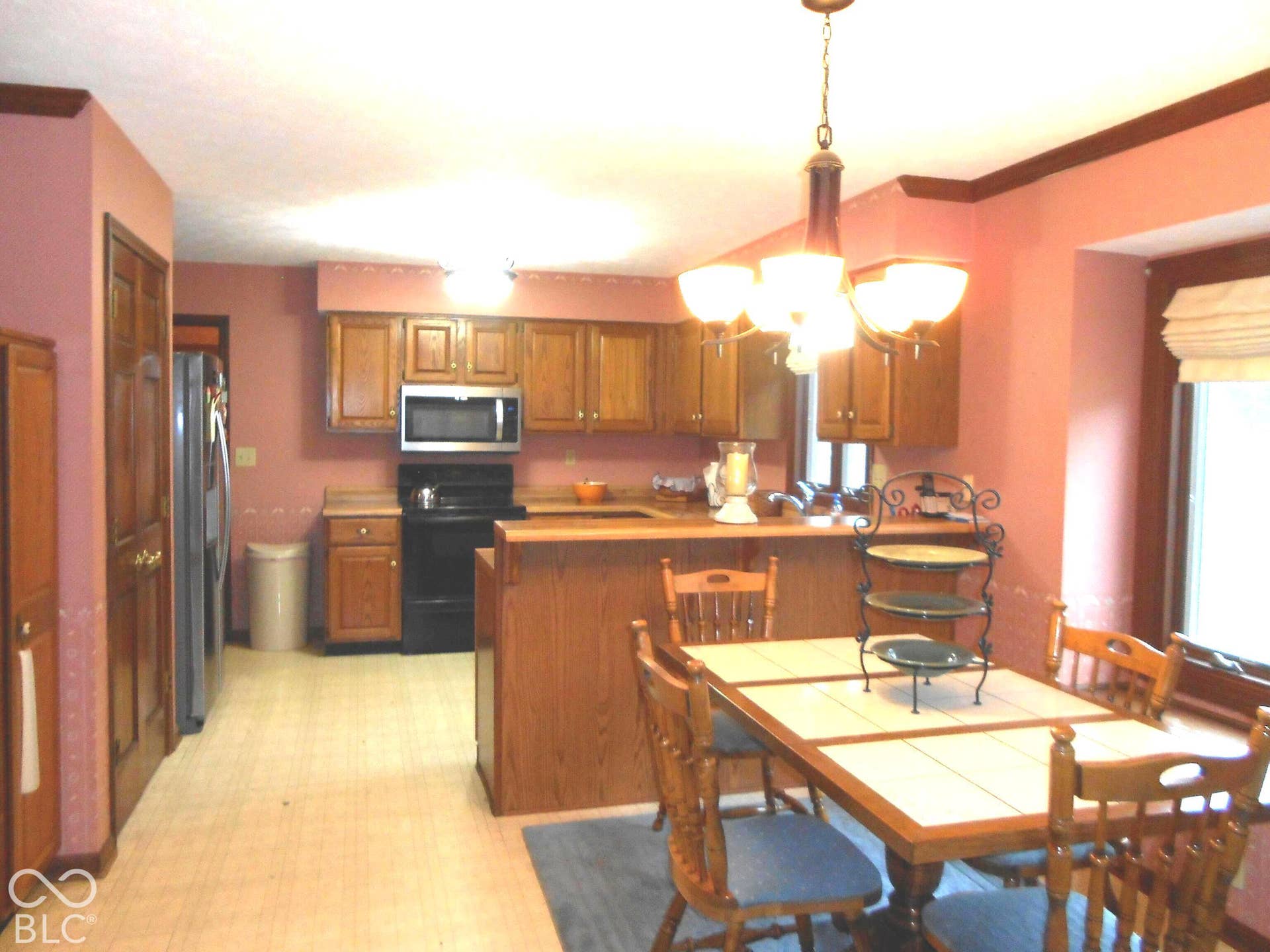 Kitchen and dining area featuring wood cabinetry, stainless steel microwave, crown molding, pantry.