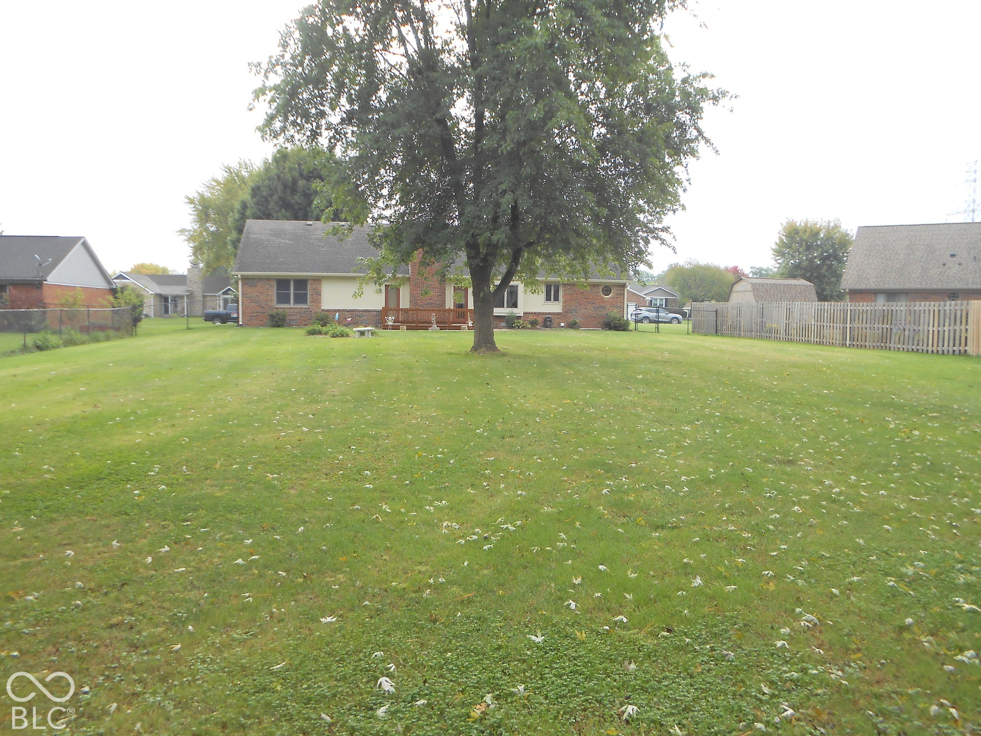 Expansive lawn with mature trees and a fenced perimeter