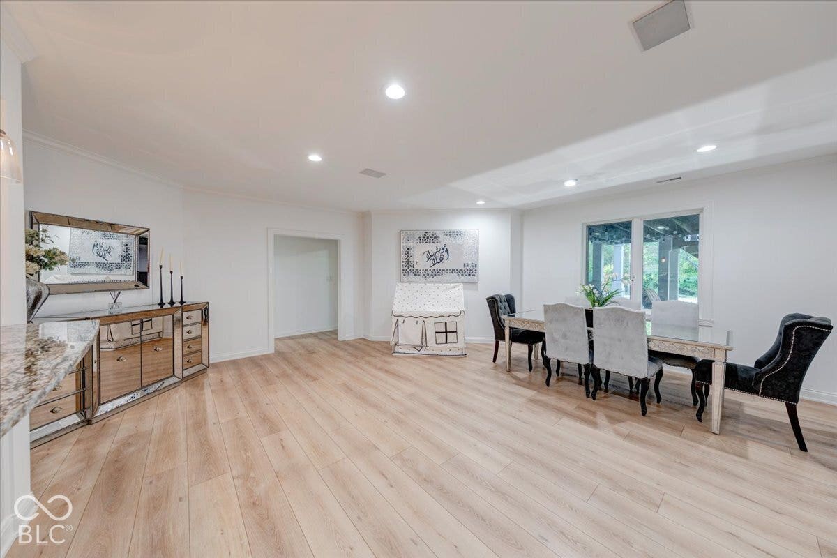 Spacious room featuring light wood-finish flooring, recessed lighting, and white walls