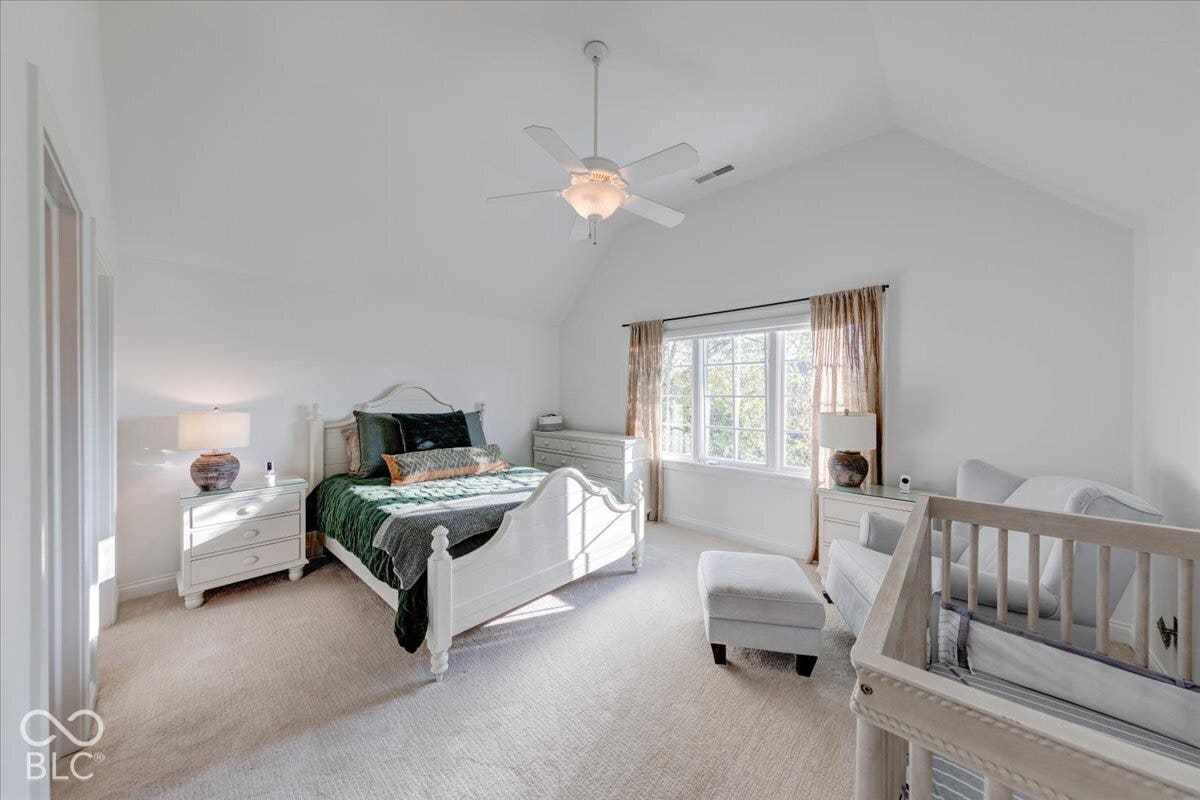 Vaulted ceiling with a ceiling fan, light-toned carpeting, and a multi-pane window