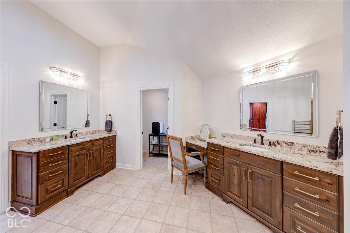 Dual wood-finish vanities with stone countertops, integrated sinks, and individual mirrors