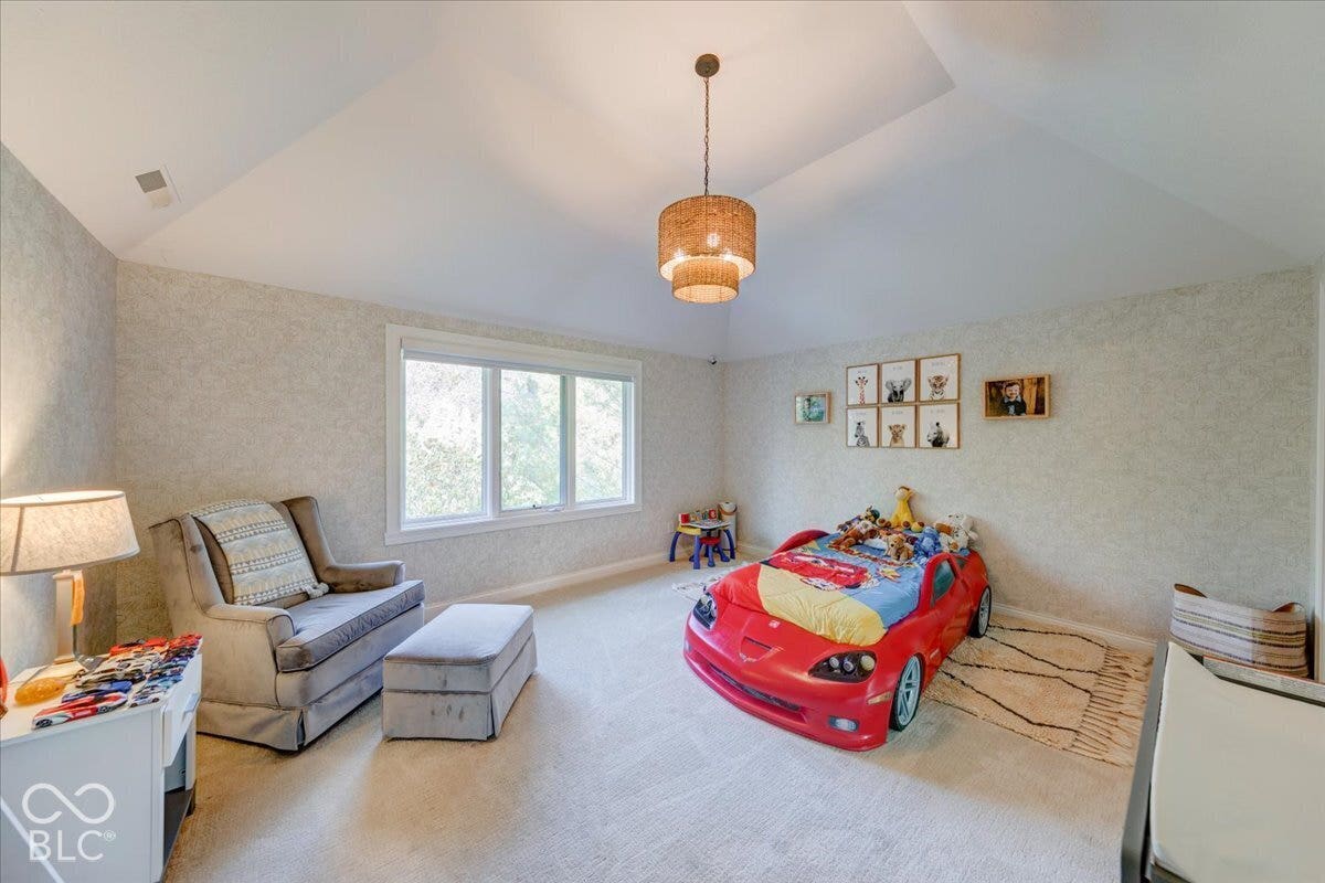 Vaulted ceiling with a tiered pendant light fixture, large window, and textured wall covering