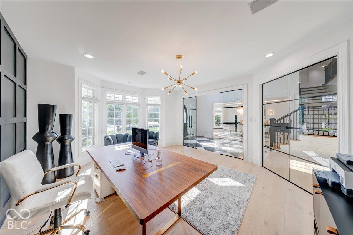 Light wood-finish flooring with a bay window, modern sputnik chandelier, and expansive glass-paned doors