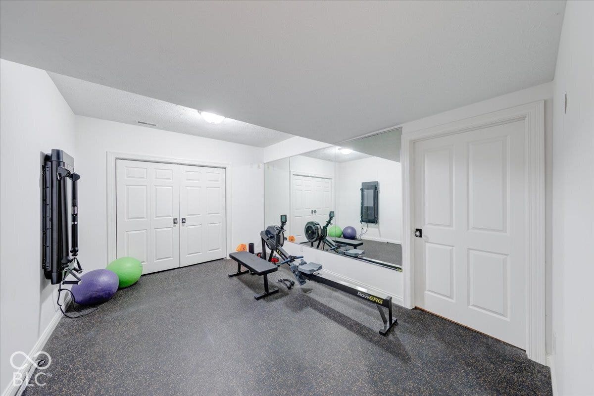 Recessed lighting illuminates the space, featuring a full-wall mirror, double bifold closet doors, and dark resilient flooring