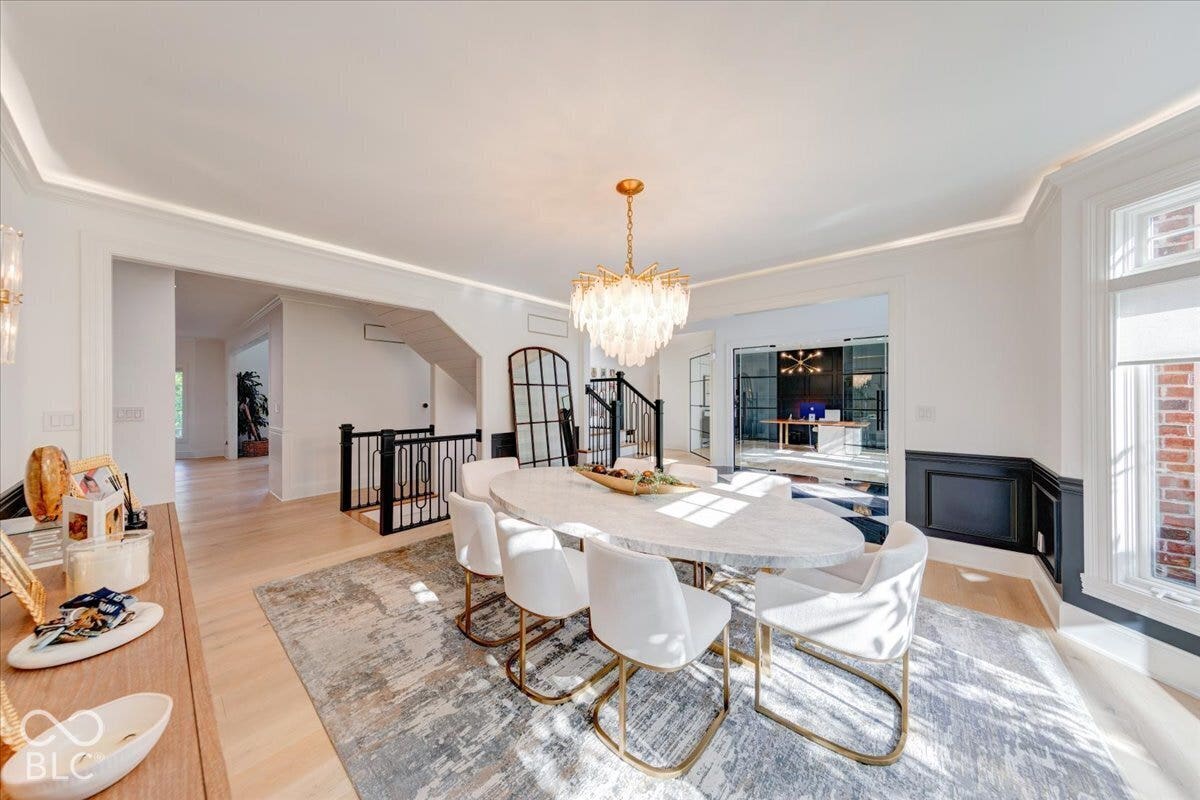 Recessed ceiling lighting, wood-finish flooring, half-wall wainscoting, and a decorative chandelier