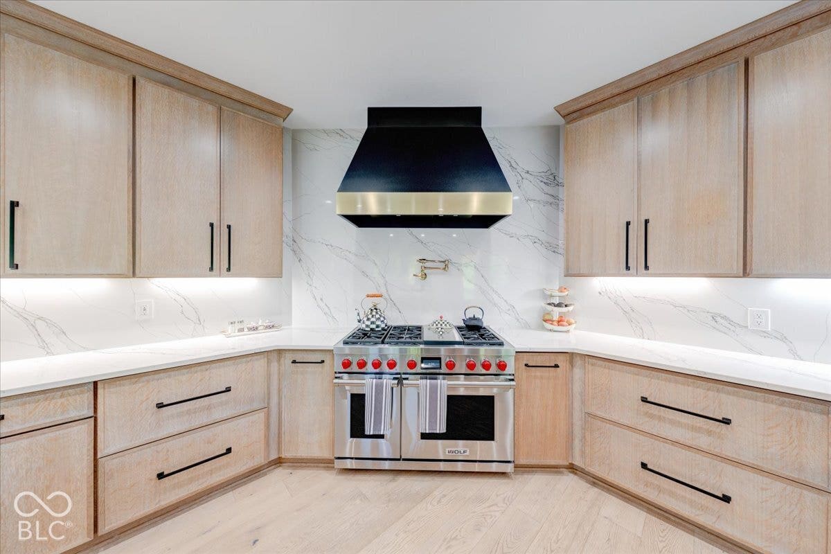 Custom cabinetry with under-cabinet lighting, stainless steel range, and white countertops