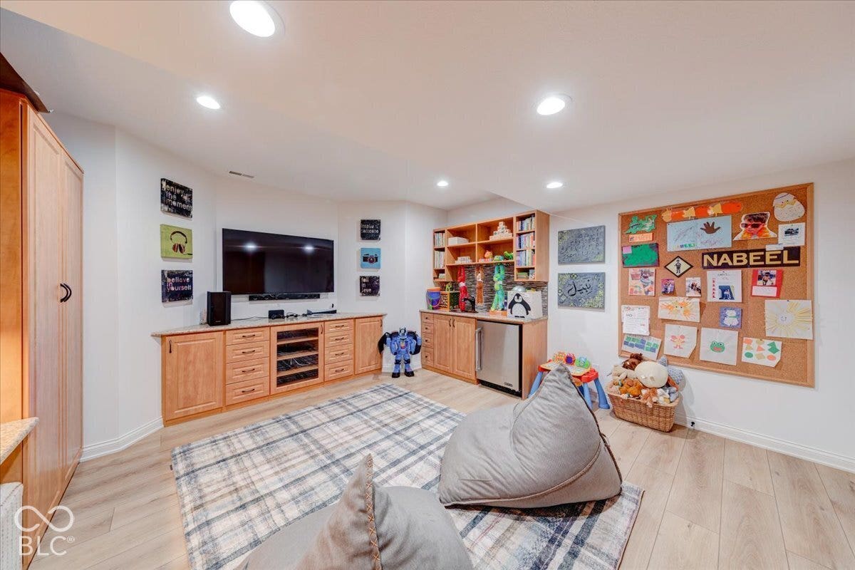 Recessed lighting, wood-finish flooring, built-in media cabinetry, additional built-in cabinetry, and a beverage refrigerator