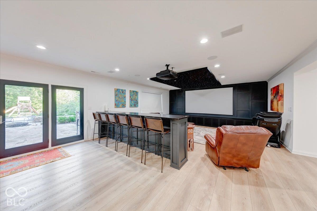 Wood-finish flooring throughout, recessed lighting, and a built-in media wall with a projector screen
