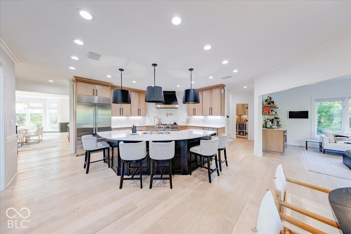 Gourmet kitchen with a large island, wood-finish flooring, recessed lighting, stainless steel appliances, and custom cabinetry