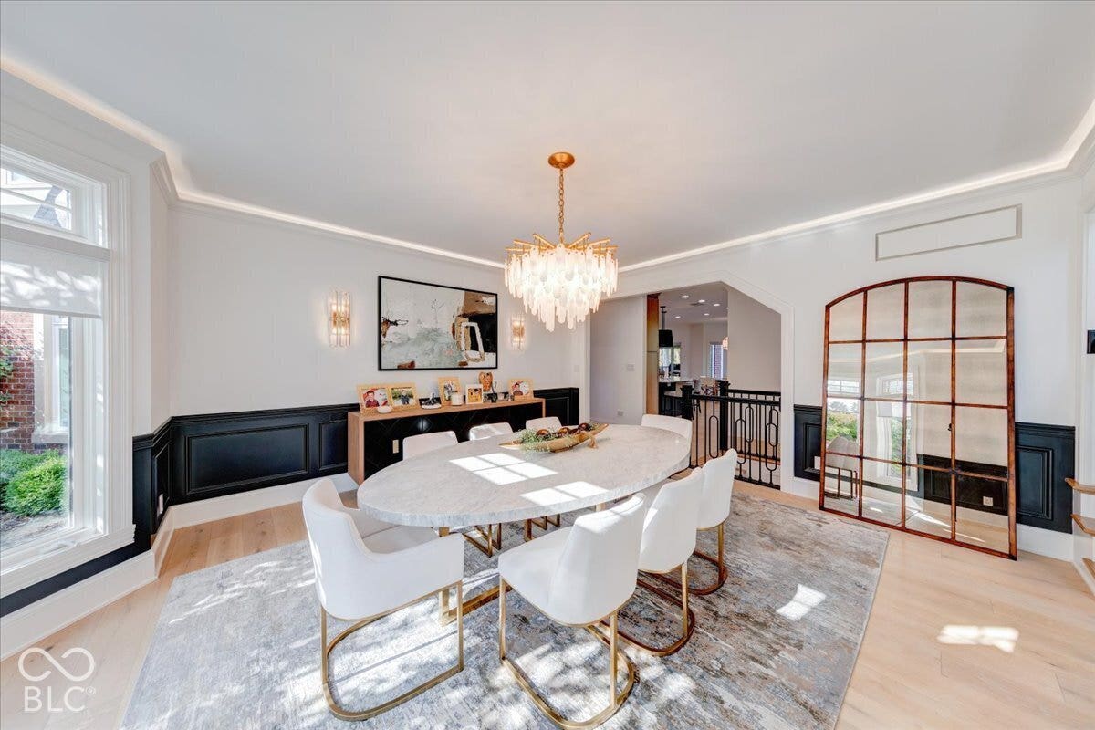 Hardwood flooring, crown molding with integrated lighting, wainscoting, and a decorative chandelier