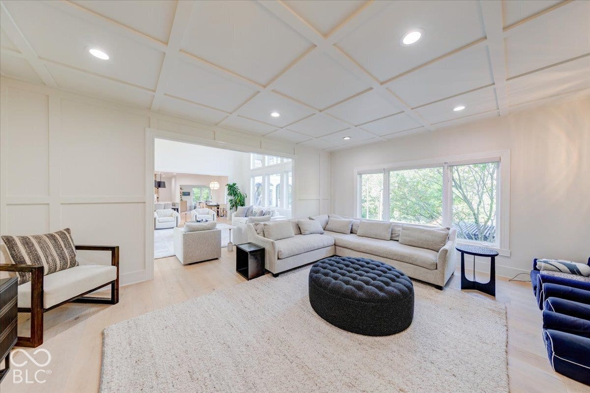 Coffered ceiling, recessed lighting, wood-finish flooring, white paneling, and large windows