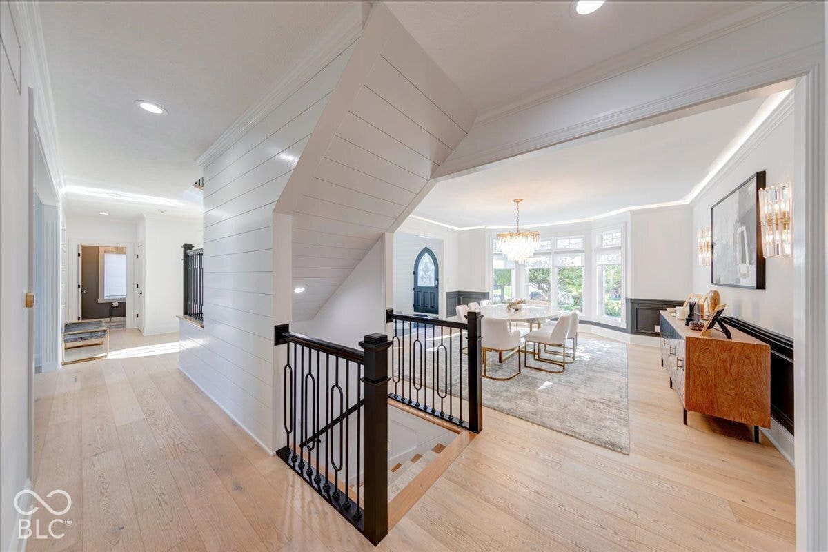 Open concept living area with wood-finish flooring, shiplap wall accents, iron staircase balusters, and recessed lighting