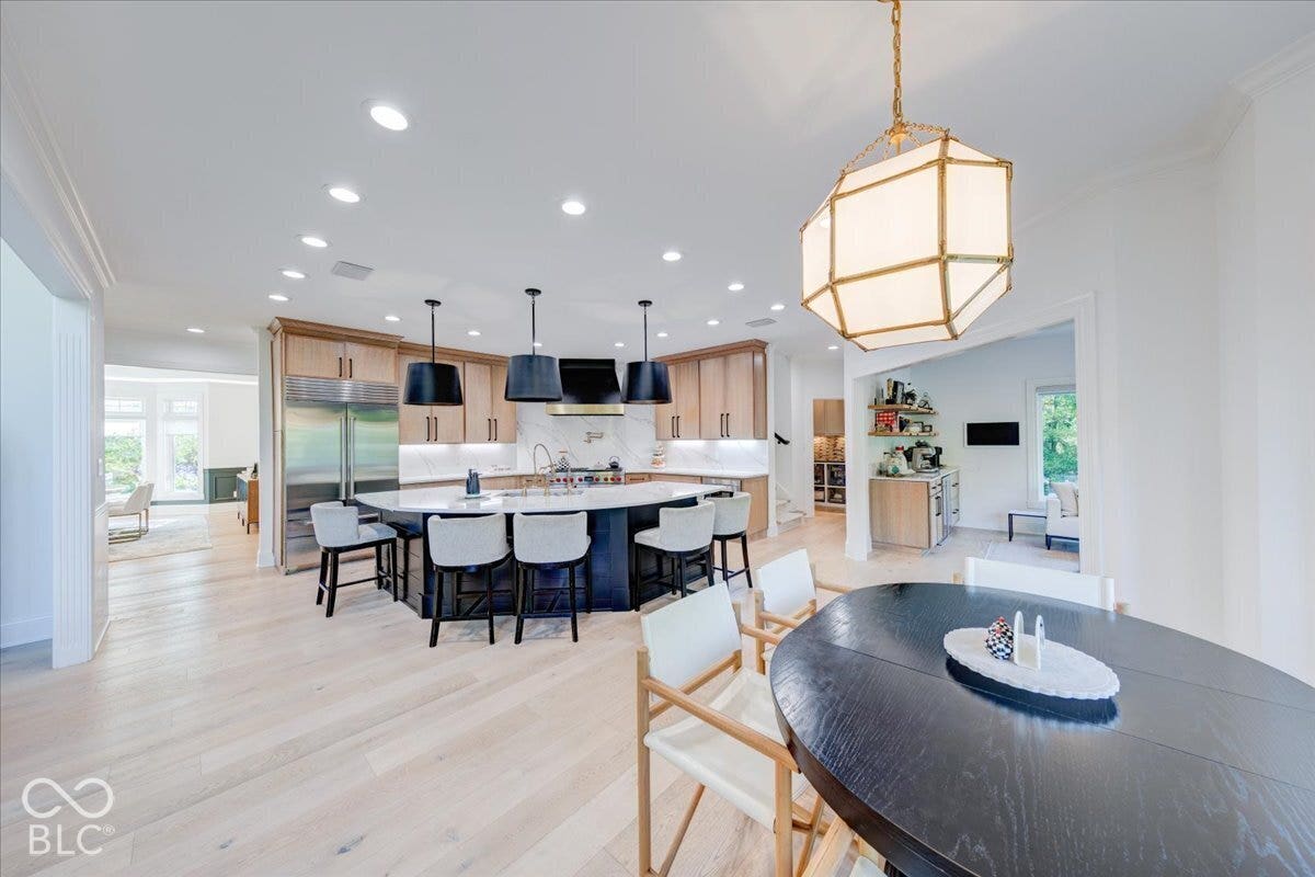 Expansive kitchen with a large central island, stainless steel refrigerator, and wood-finish cabinetry