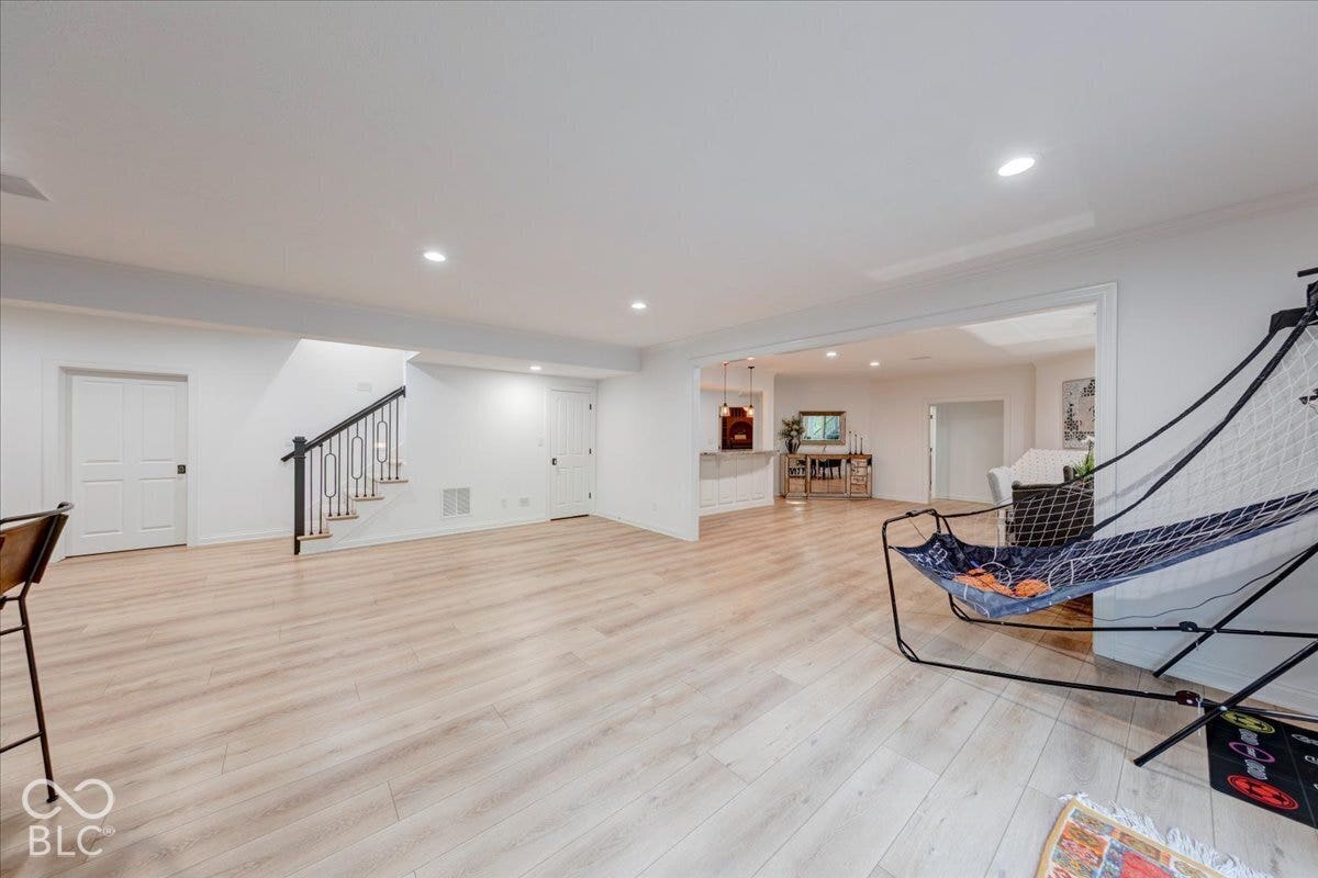 Spacious open-concept room featuring light wood-finish flooring, recessed lighting, and white trim