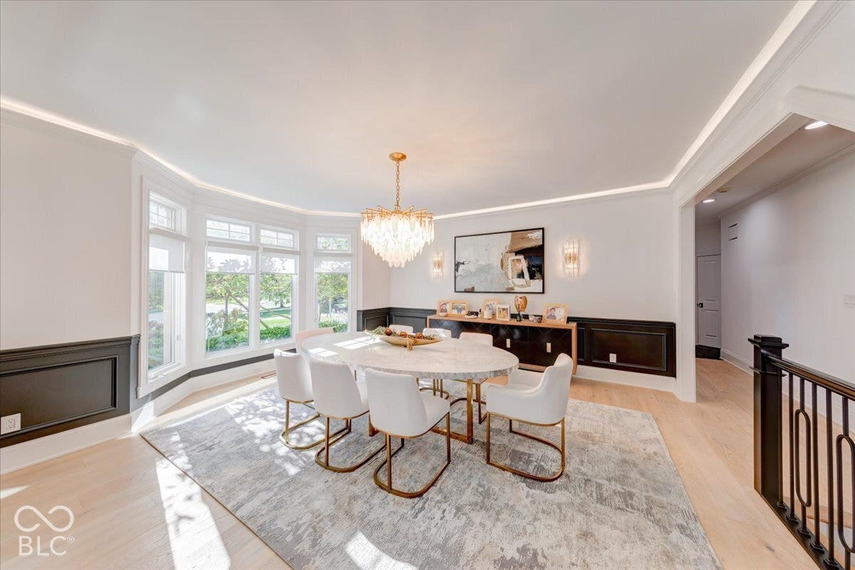 Bay window with multiple panes, crown molding, light wood-finish flooring, and a chandelier