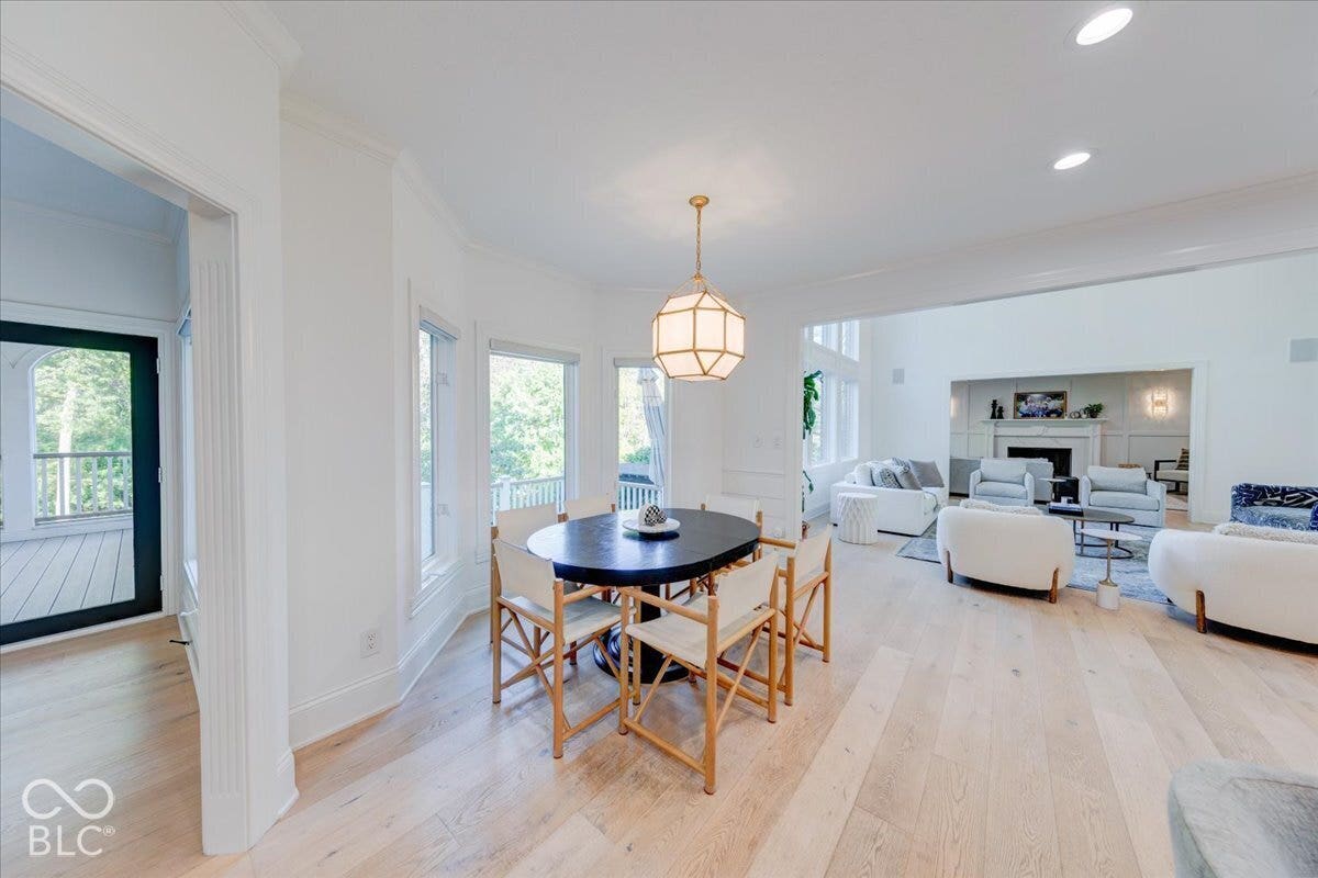Open-concept living space featuring light wood-finish flooring, recessed lighting, and a prominent fireplace with mantel