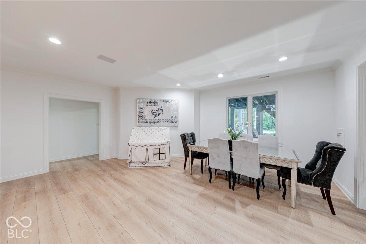 Recessed lighting, wood-finish flooring, white walls, and a large window
