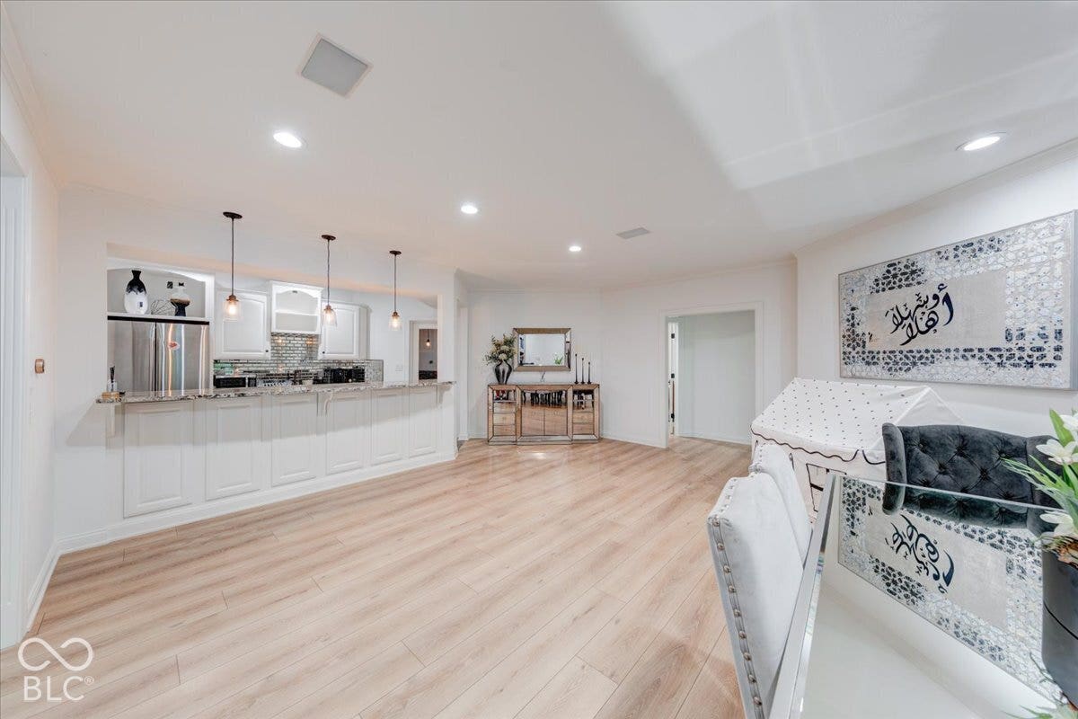 Open-concept living area with wood-finish flooring, recessed lighting, and a kitchen bar featuring pendant lights