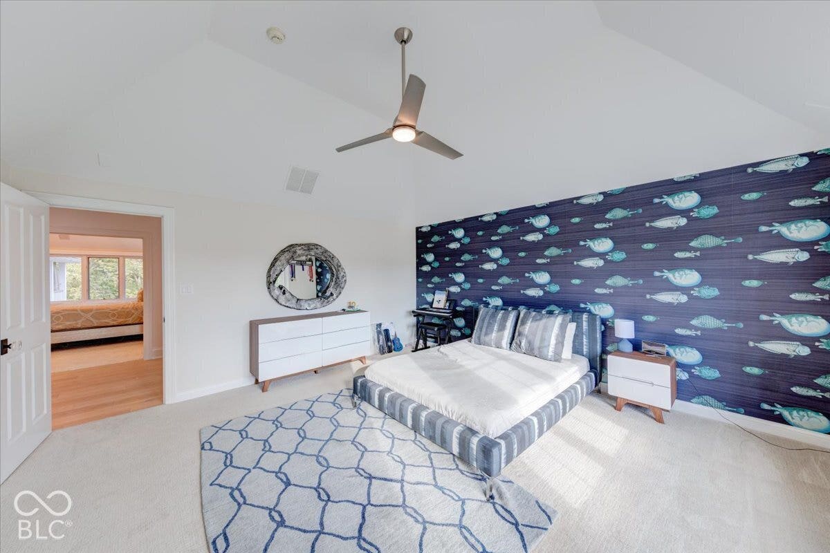 Spacious primary bedroom featuring vaulted ceilings, a brushed nickel ceiling fan, and abundant natural light from multiple windows