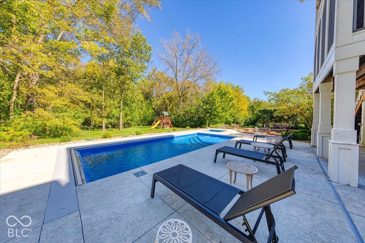 Spacious backyard featuring an in-ground swimming pool, an integrated hot tub, and a large paved patio area