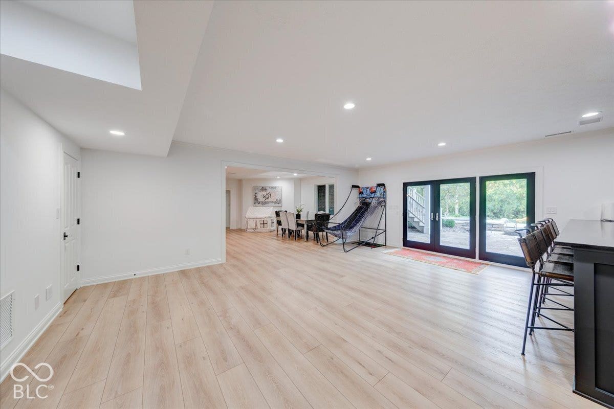 Spacious room with light wood-finish flooring, recessed lighting, and white walls