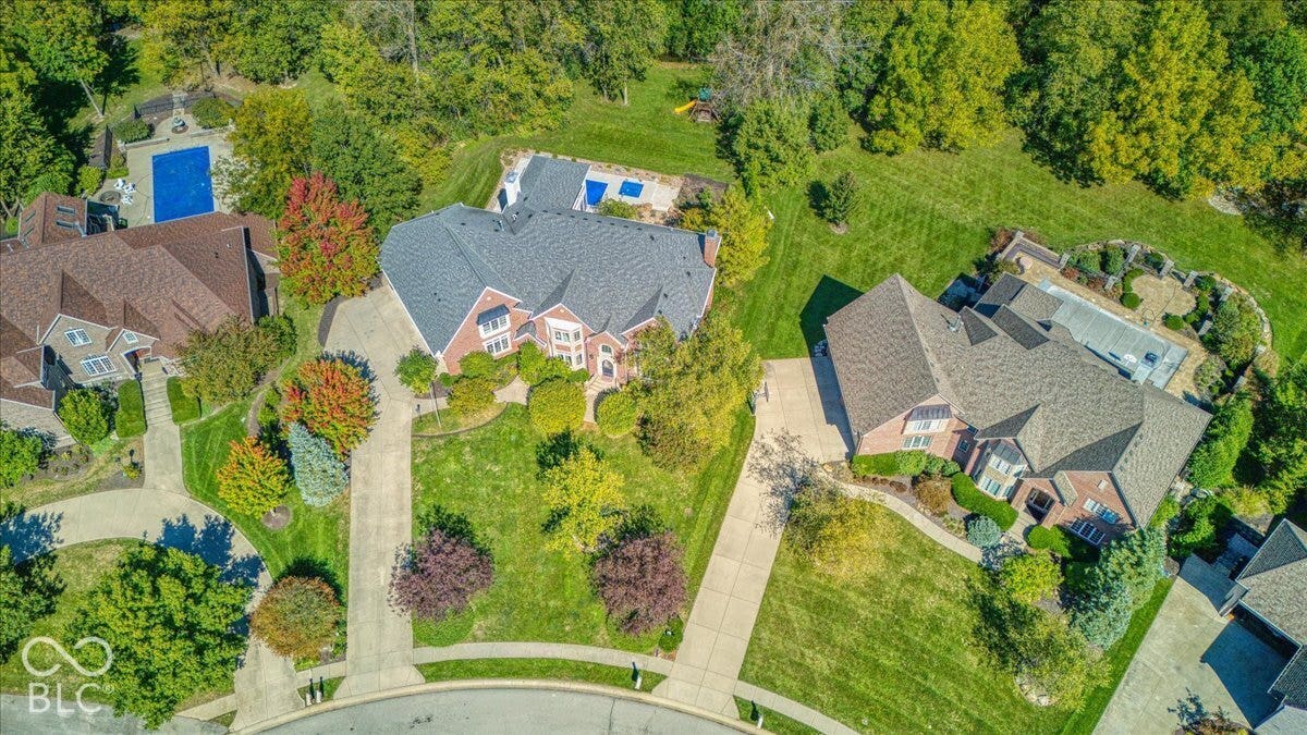 Expansive property featuring a large residence with a multi-gabled roof, extensive green landscaping, mature trees, and a concrete driveway