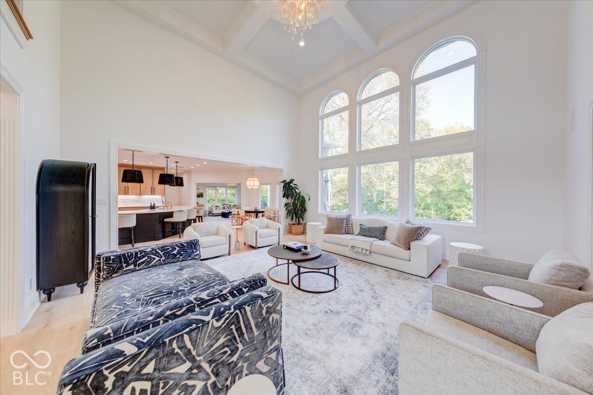 Two-story living area featuring a coffered ceiling, large arched windows, and light wood-finish flooring