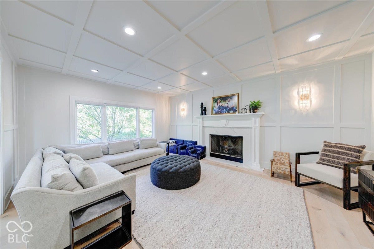 Coffered ceiling, decorative wall paneling, fireplace with mantel, recessed lighting, and light wood-finish flooring