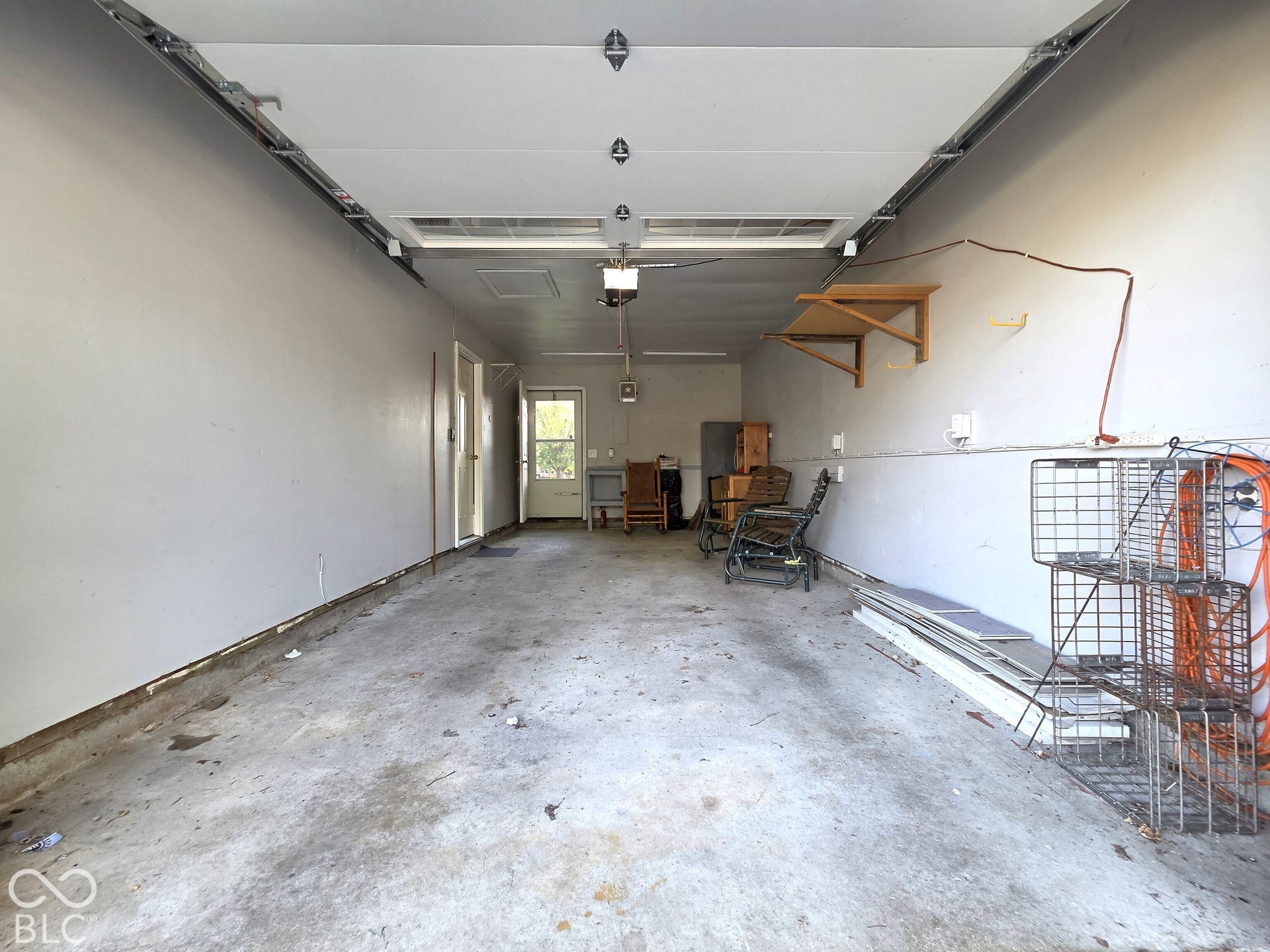 1221 Elk Lane, Elwood, IN 46036 Attached garage featuring concrete flooring, wall-mounted shelving, and a pedestrian door