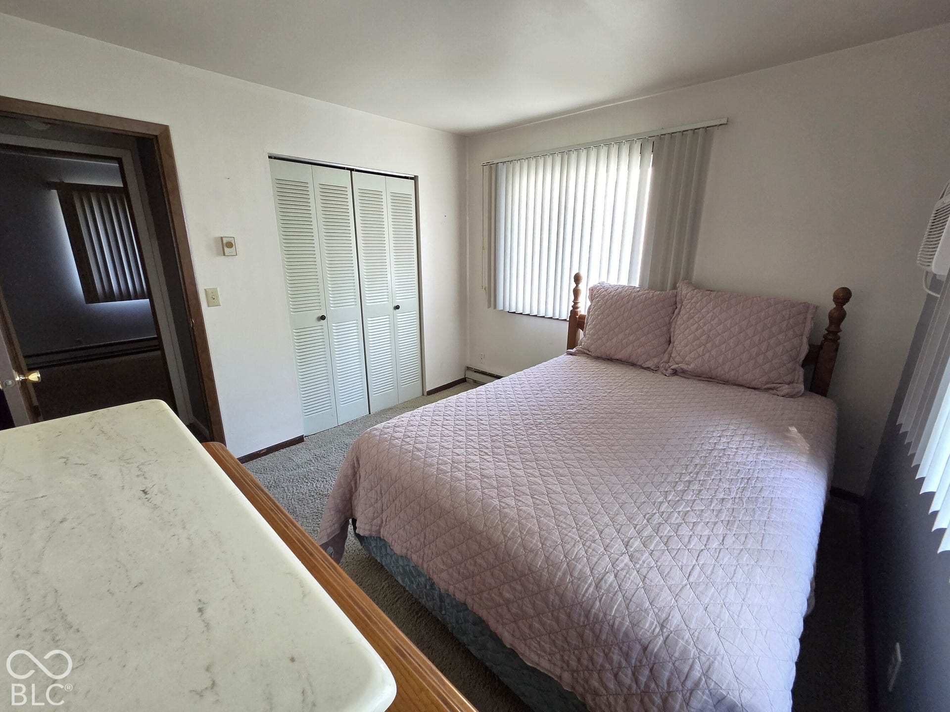 1221 Elk Lane, Elwood, IN 46036 Room featuring neutral wall-to-wall carpeting, floor-to-ceiling vertical blinds, and a built-in double-door closet with louvered panels