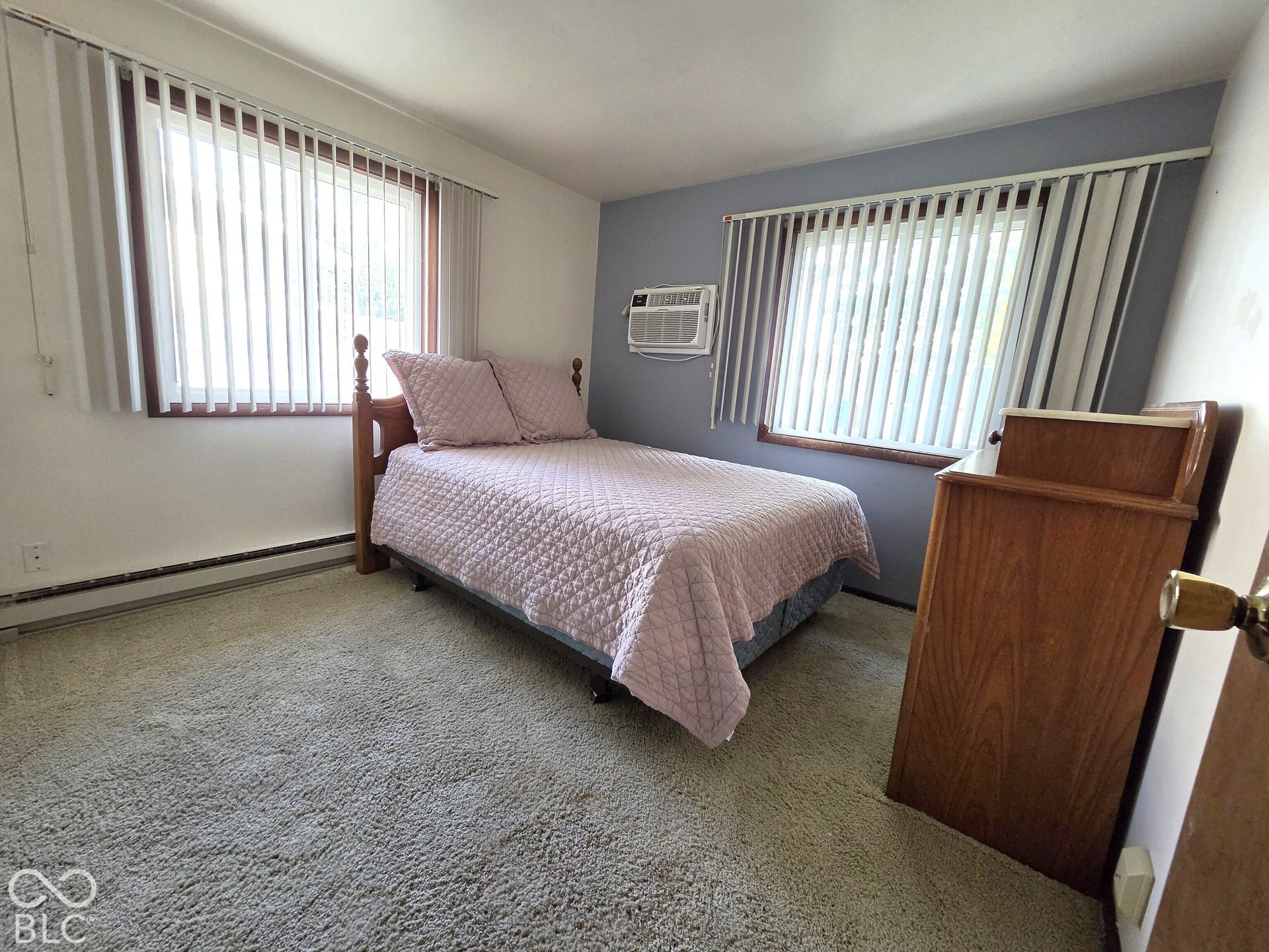 1221 Elk Lane, Elwood, IN 46036 Bedroom featuring carpeting, dual windows with vertical blinds, wall-mounted air conditioning unit, and accent wall