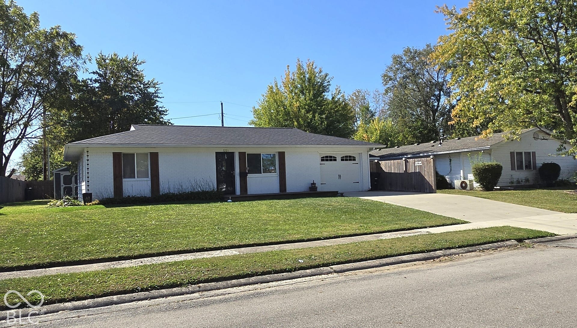1221 Elk Lane, Elwood, IN 46036 White siding exterior with a dark shingle roof, attached garage, well-maintained lawn, and a concrete driveway