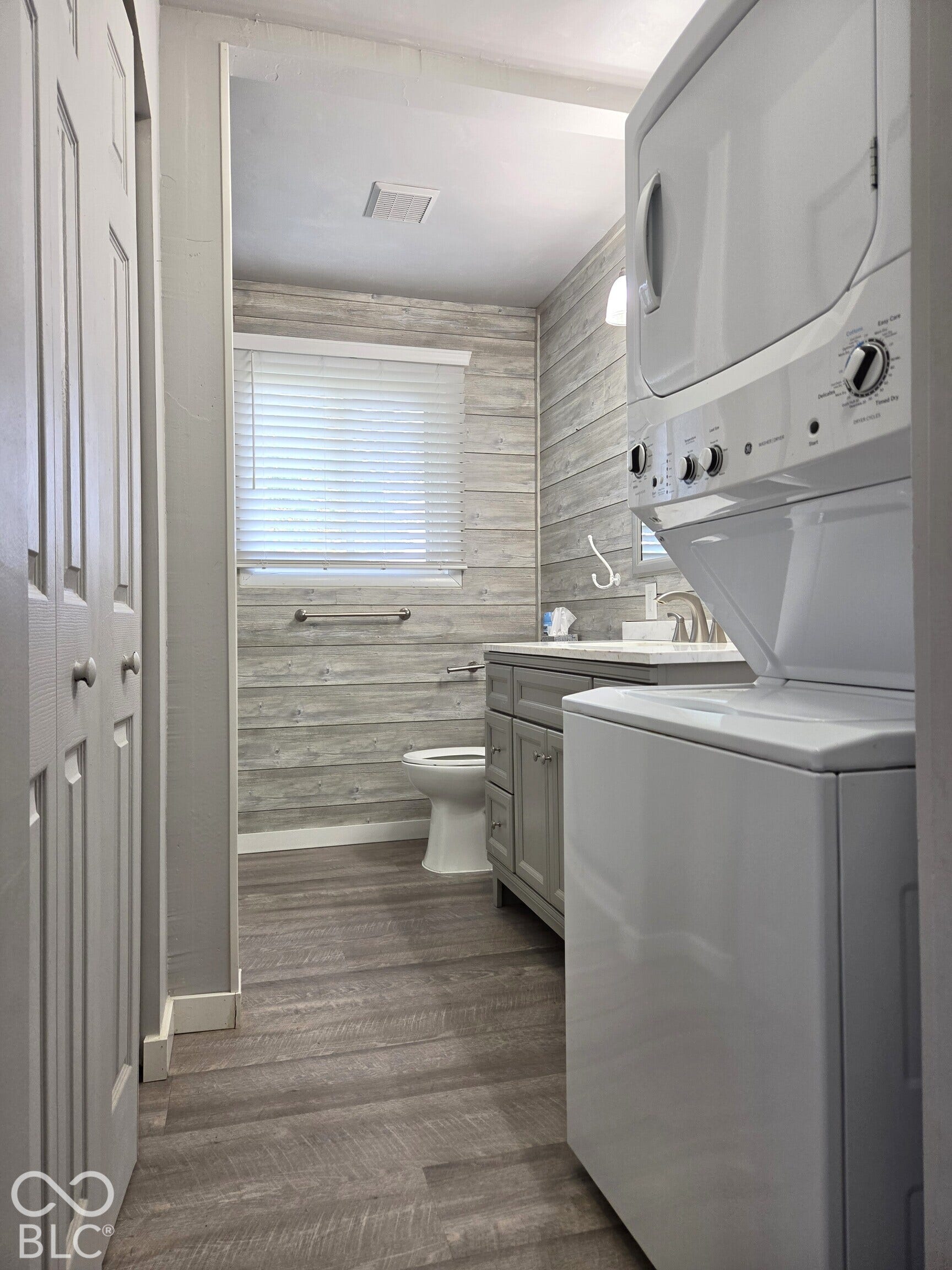 1221 Elk Lane, Elwood, IN 46036 Bathroom featuring wood-finish flooring, a white stacked washer and dryer, and a grey vanity with a white countertop