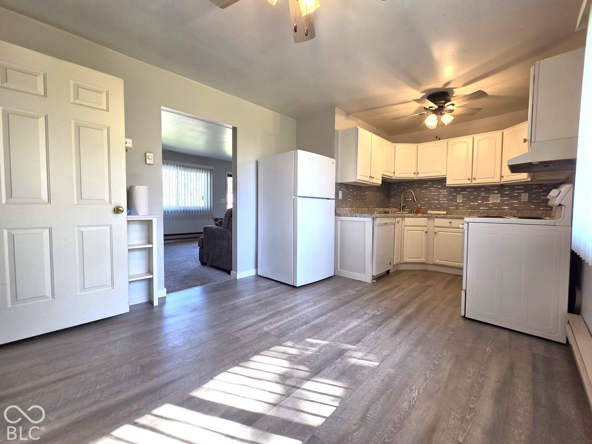 1221 Elk Lane, Elwood, IN 46036 Kitchen featuring white cabinetry, gray tile backsplash, light-toned countertops, and wood-finish flooring