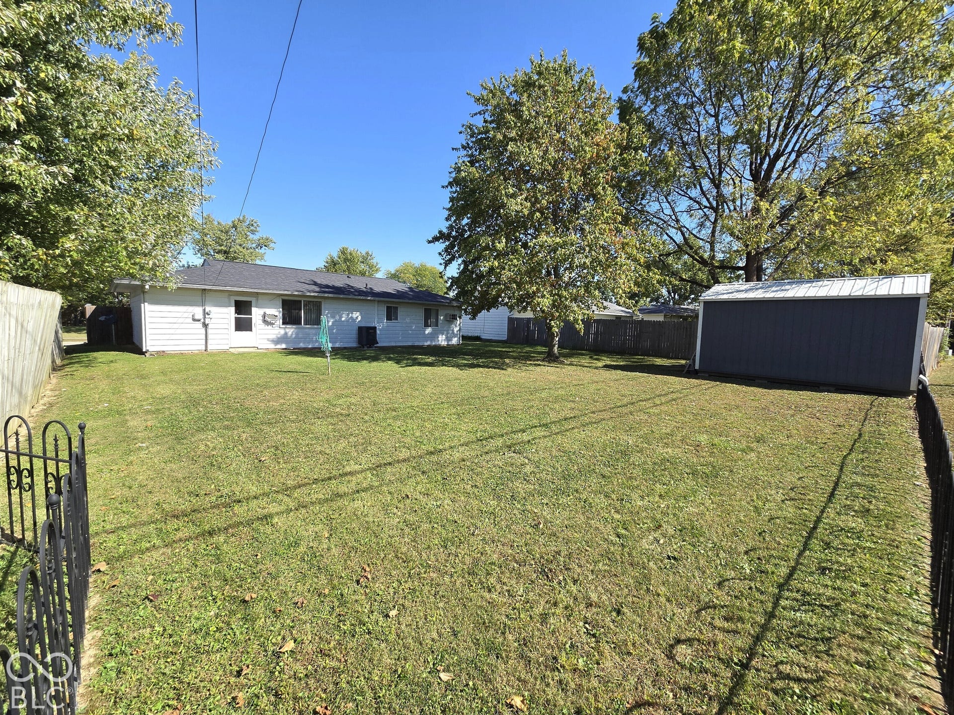 1221 Elk Lane, Elwood, IN 46036 Expansive lawn featuring a detached shed with a metal roof, mature trees, and a privacy fence