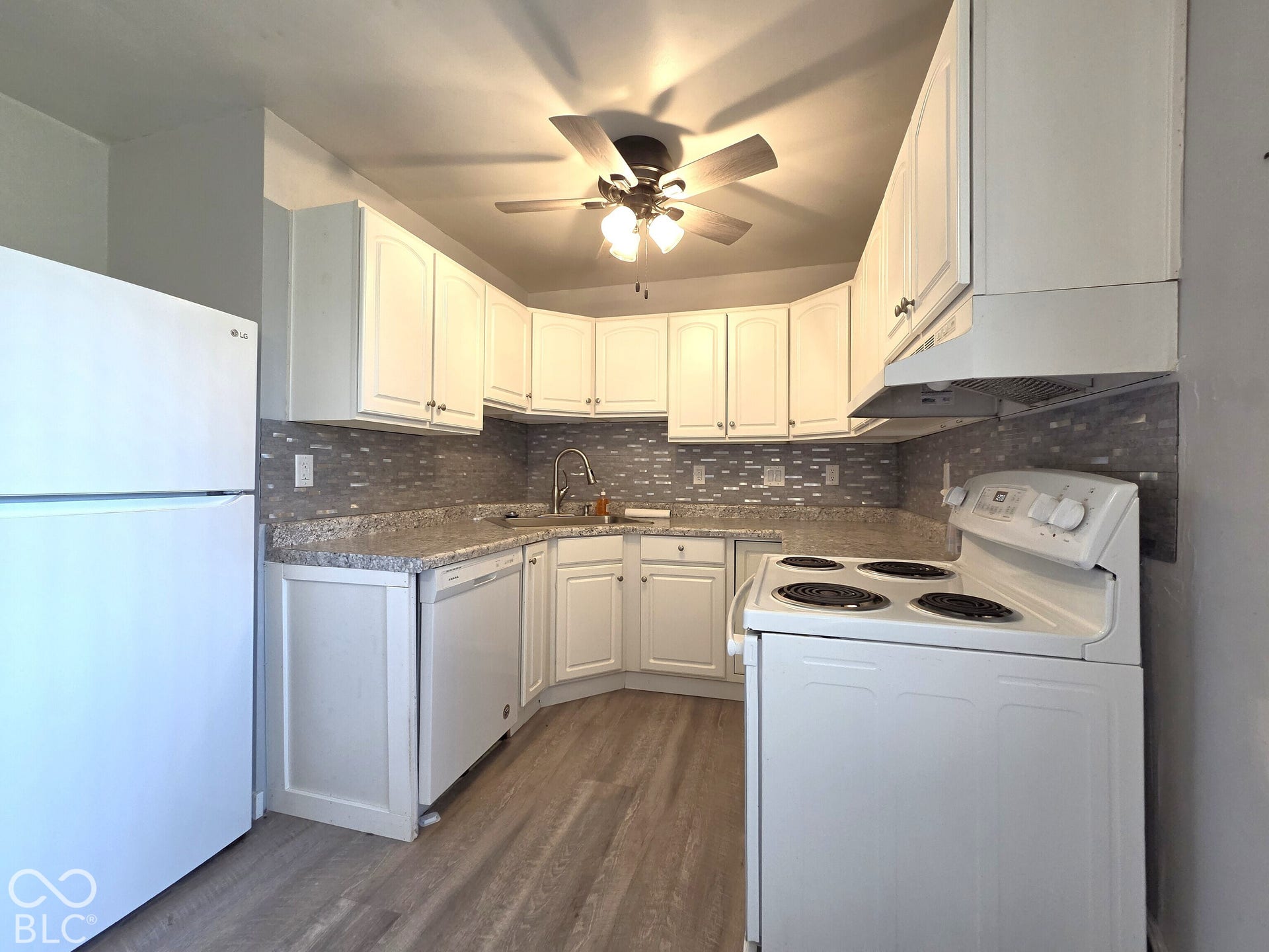 1221 Elk Lane, Elwood, IN 46036 Kitchen featuring white cabinetry, grey tile backsplash, light-toned countertops, wood-finish flooring, and a ceiling fan