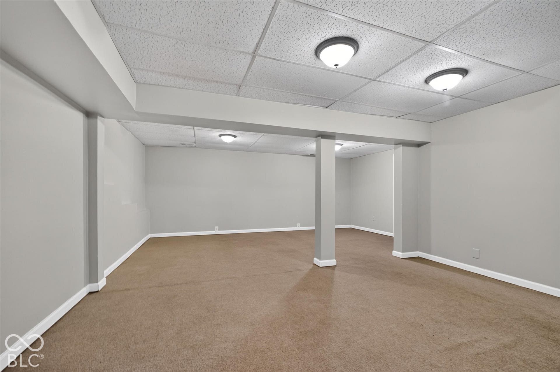 Expansive finished basement with carpeted flooring and neutral wall color