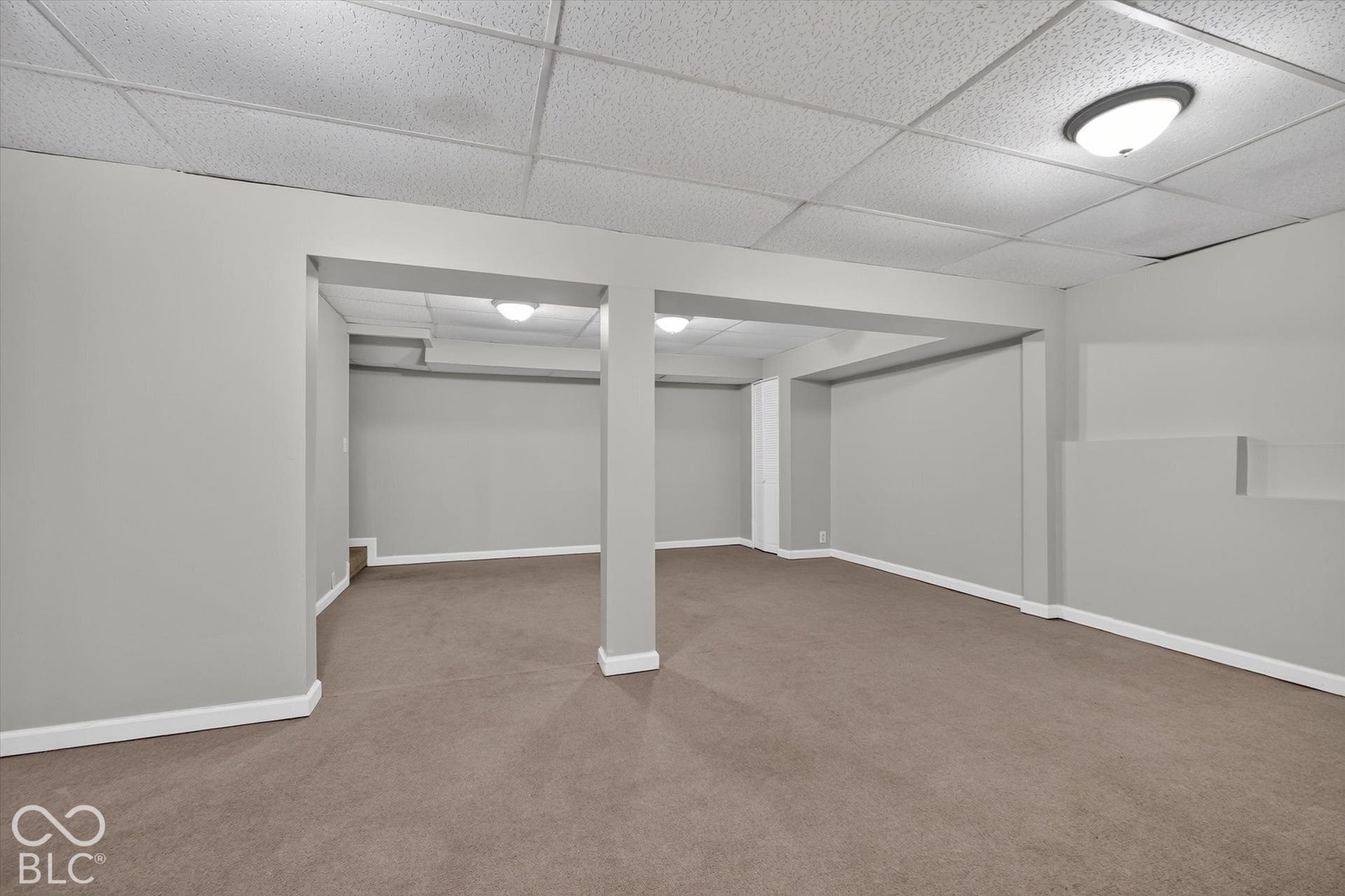 Expansive finished basement with carpeted flooring and neutral wall color