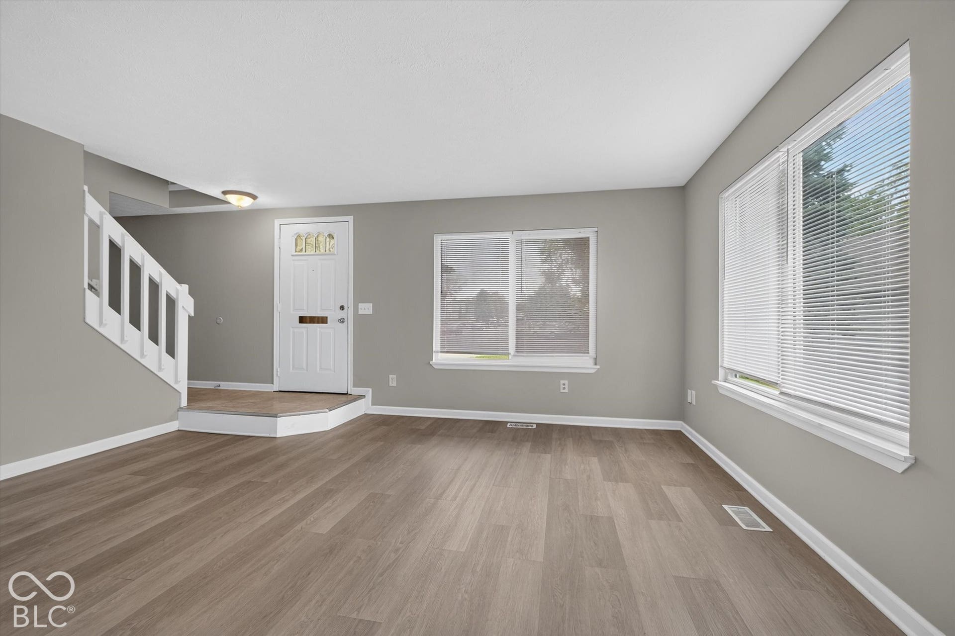 Living room and entryway with abundant natural light and neutral paint