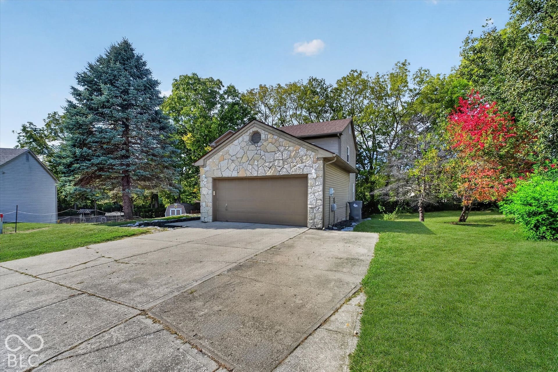 Front of home featuring a paved driveway, attached garage, and spacious front yard