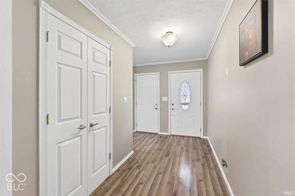 Welcoming foyer showcasing wood-finish flooring, recessed ceiling lighting, and double-door closet storage