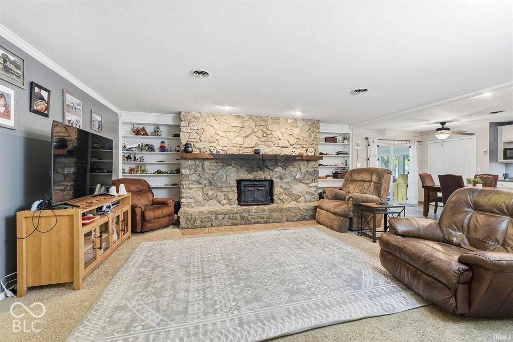 Spacious family room anchored by a stone fireplace with built-in shelving, recessed lighting, and ceiling fan