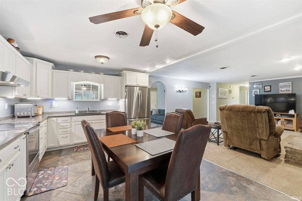 White cabinetry with under-cabinet lighting, stainless steel appliances, and a wood-finish ceiling fan