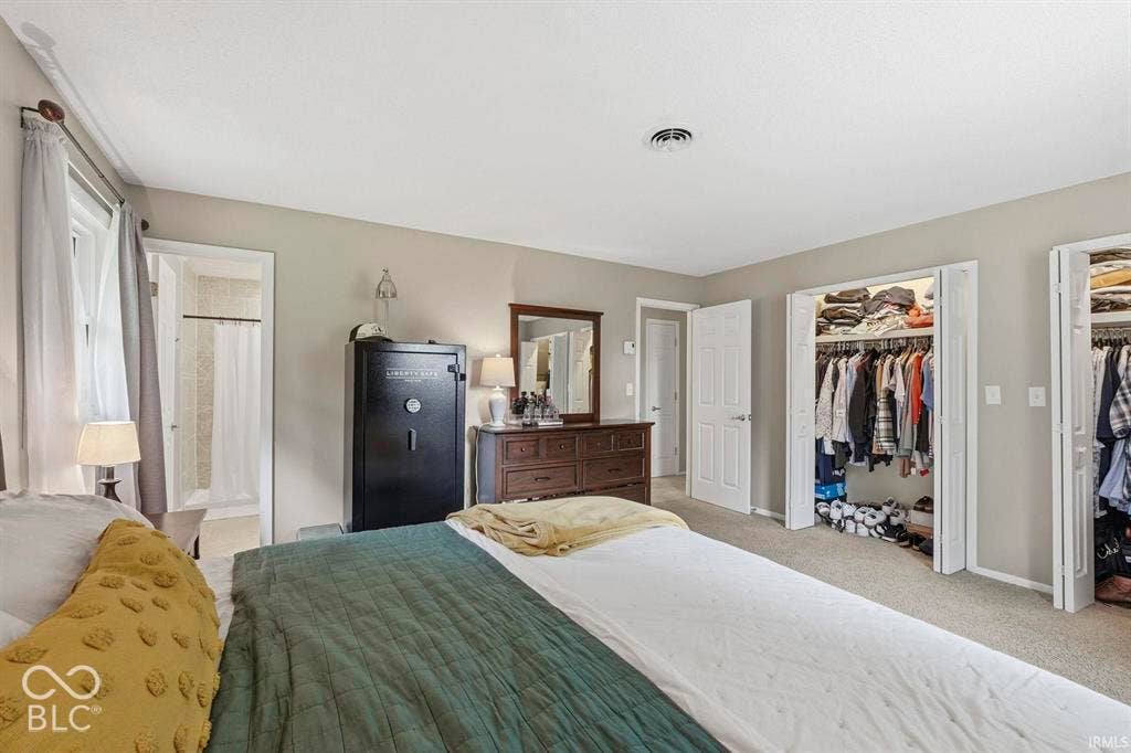 Spacious primary bedroom suite featuring neutral wall finishes, recessed ceiling lighting, and direct access to dual walk-in closets