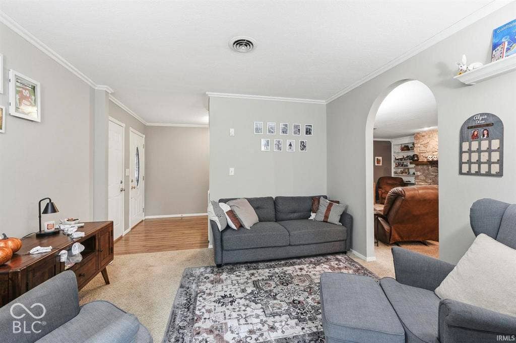 Bright, open living room showcasing wood-finish flooring, neutral wall finishes, and multiple seating areas