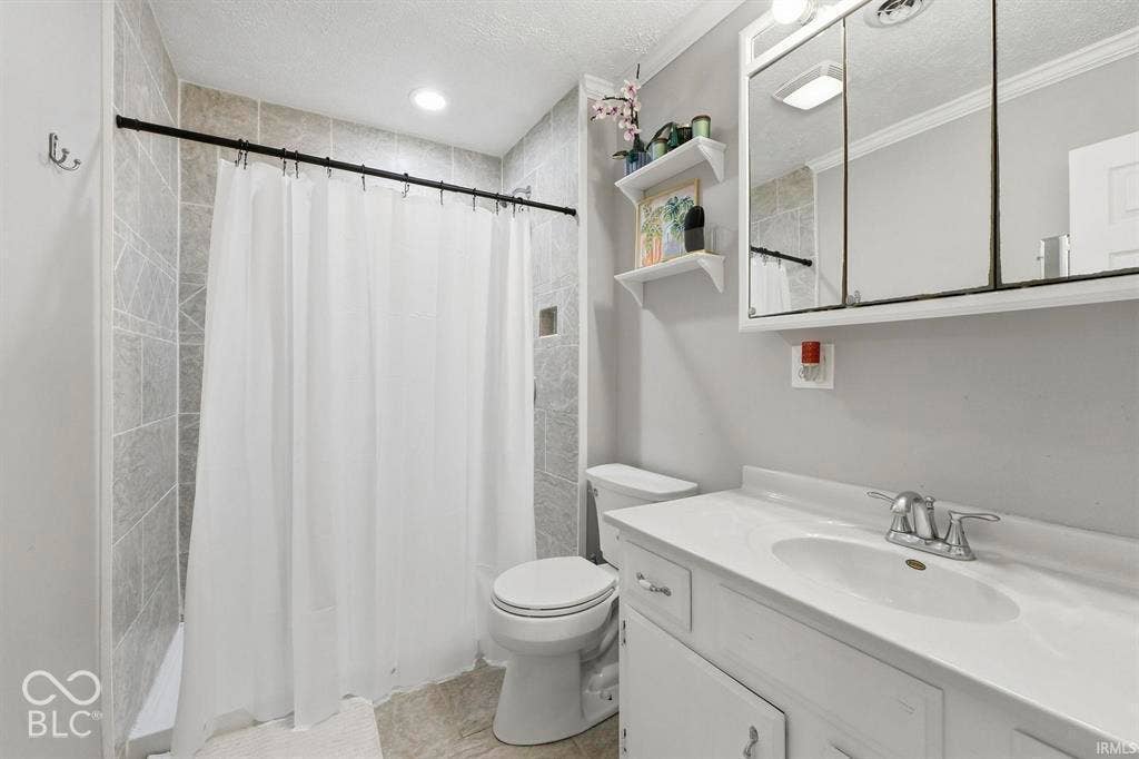 Modern bathroom featuring a white vanity with integrated sink and chrome faucet, mirrored medicine cabinet with integrated lighting, tile-lined shower enclosure with white subway tile and chrome fixtures, and ceramic toilet